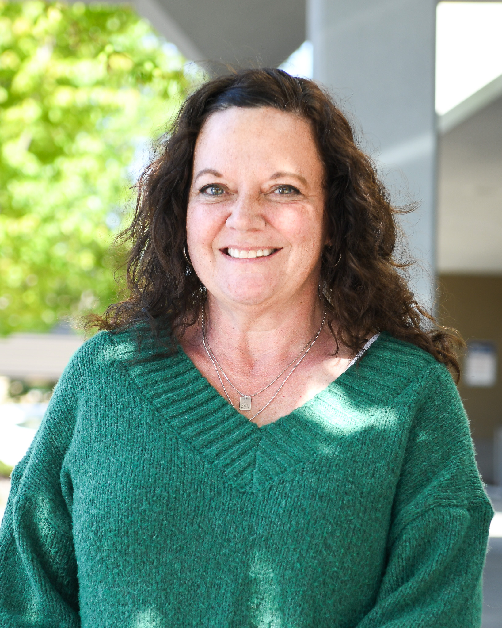 Woman in a green sweater smiles at the camera