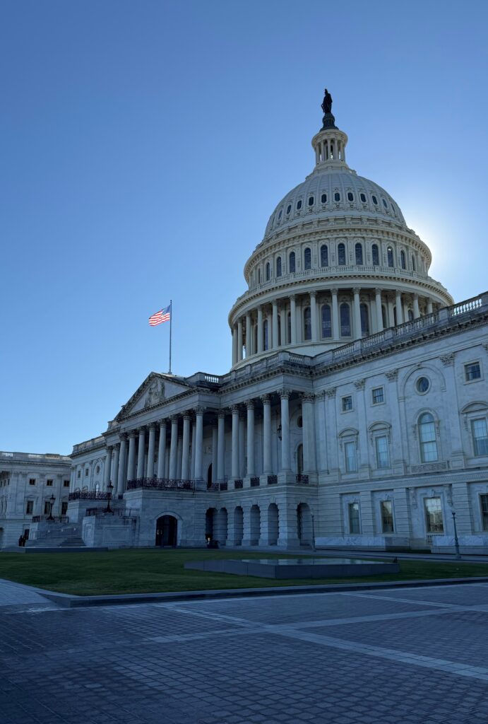 The United States Capitol building with the sun peeking behind the dome
