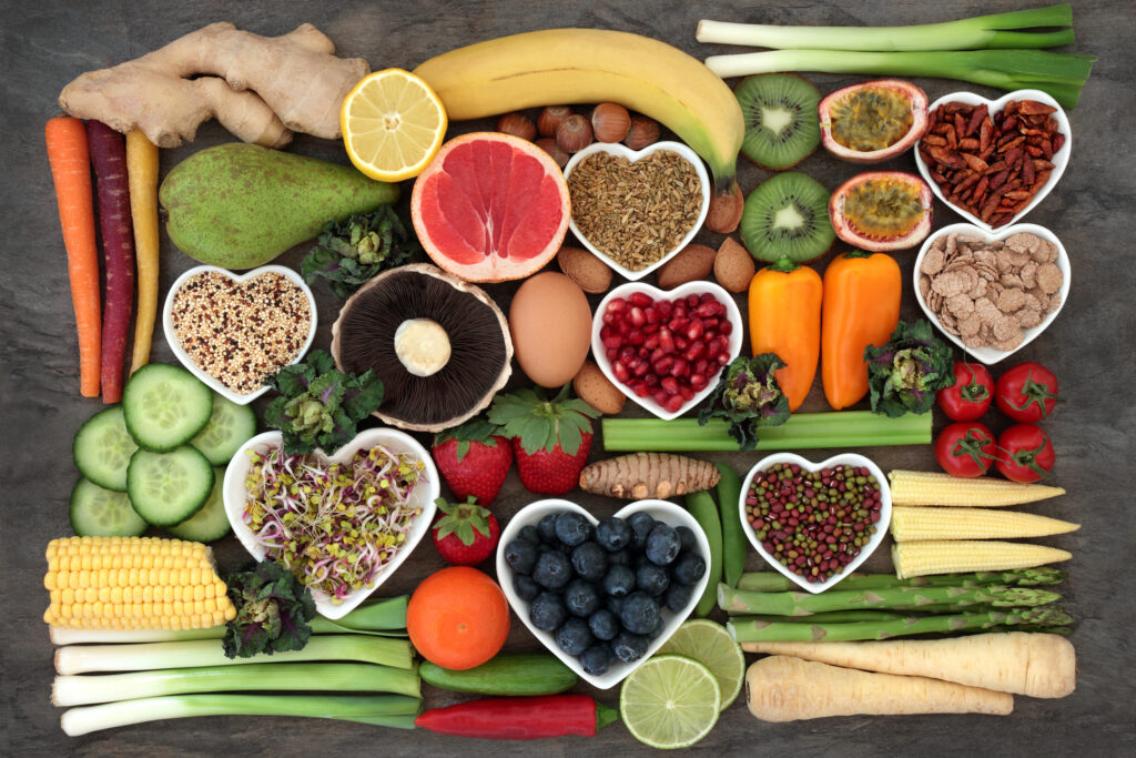 fruits an vegetables arranged artistically with berries and nuts in heart shaped bowls punctuating the display. 