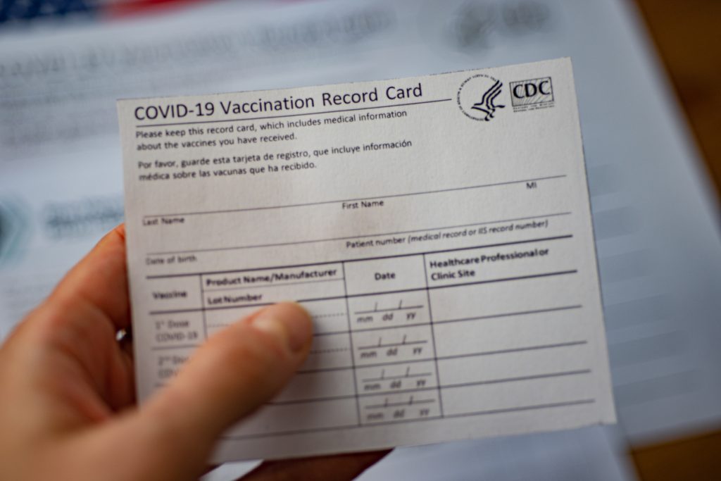 Close up view of blurred COVID-19 Vaccination Record Card by CDC in hand.