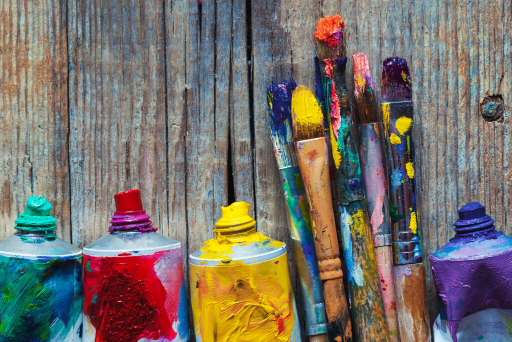 Tubes of oil paint and artist paint brushes closeup on wooden background. Retro styled.