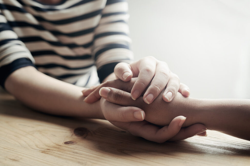 Shot of an unidentifiable woman consoling a friend by holding her hand